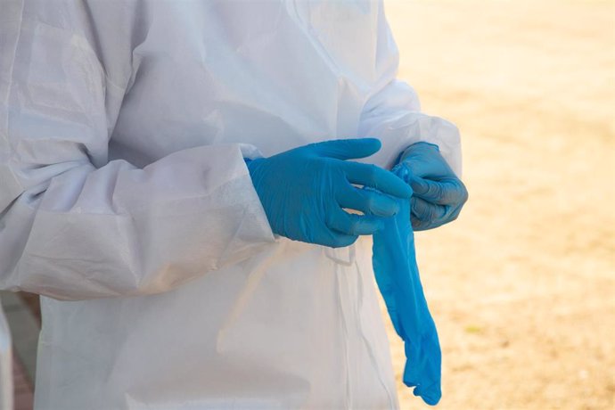 Archivo - Un sanitario se pone los guantes para preparar una dosis de vacuna