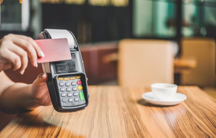 Una persona paga con una tarjeta bancaria en un bar.