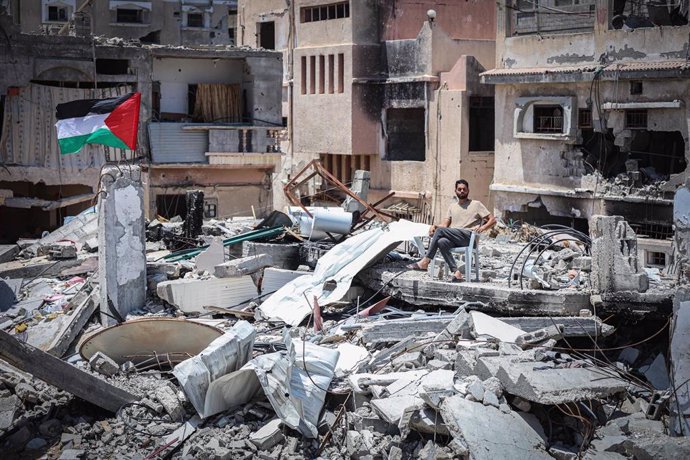 Un hombre sentado entre los escombros de su casa destruida por los ataques de Israel.
