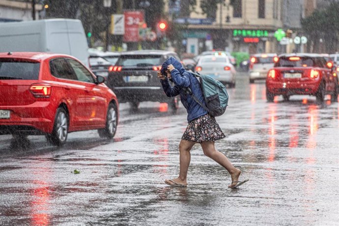 Archivo - Una mujer corre bajo la lluvia en València (archivo)