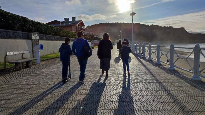 Archivo - Una familia paseando por la playa de Salinas, en Castrillón.