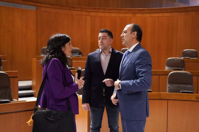 El consejero de Sanidad del Gobierno de Aragón, José Luis Bancalero Flores, conversa con la diputada de CHA Isabel Lasobras y el parlamentario del PSOE Iván Carpi, antes del inicio de la sesión plenaria.