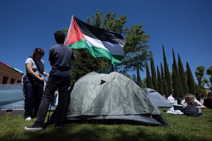 Dos estudiantes con una bandera de Palestina durante una acampada para mostrar su apoyo al pueblo palestino y exigir el fin del conflicto en Gaza, en las inmediaciones de la Casa de Estudiantes de la Universidad Complutense, a 7 de mayo de 2024, en Madrid