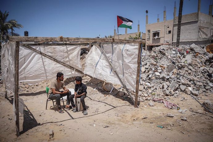 Jívenes palestinos sentados junto a unos escombros en la Franja de Gaza