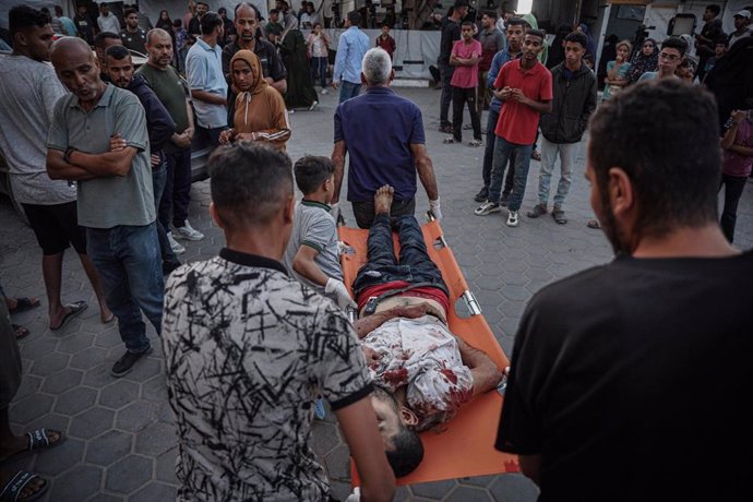 Civiles palestinos trasladan el cuerpo de un fallecido para depositarlo en la morgue en Deir al Balah, Gaza. 