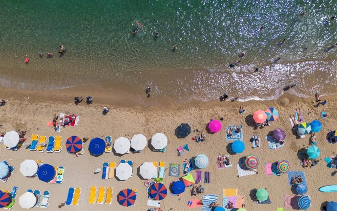 Archivo - Numerosas personas disfrutan de un día de playa en la Costa Brava