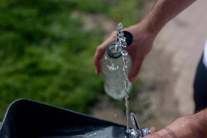Archivo - Una persona llena una botella de agua de una fuente.