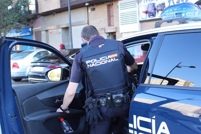 Archivo - Un agente de la Policía Nacional, entrando en un coche patrulla.