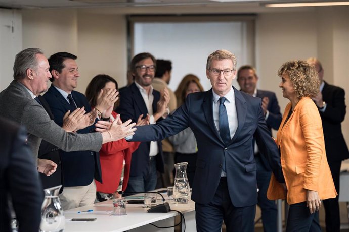 En el lado derecho de la mesa, el presidente del PP, Alberto Núñez Feijóo, y la candidata del PP a las elecciones europeas, Dolors Montserrat, saludan a miembros del partido durante la reunión del Comité Ejecutivo Nacional, en la sede del PP, a 14 de mayo