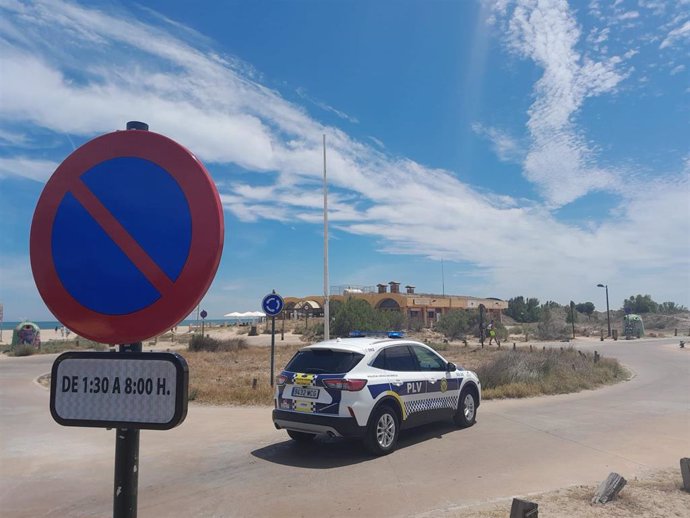 Imagen de un coche de la Policía Local de València y de una de las señalaes instaladas en el entorno de la Devesa-Albufera para prohibir el aparcamiento nocturno y las acampadas de autocaravanas.