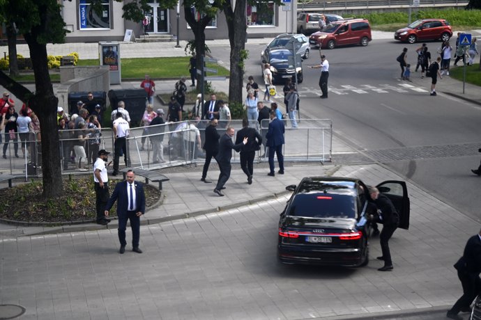 15 May 2024, Slovakia, Banska Bystrica: Bodyguards take Slovakian Prime Minister Robert Fico to safety in a car from the scene of the incident. Fico had been shot and injured after a cabinet meeting in the town of Handlova.