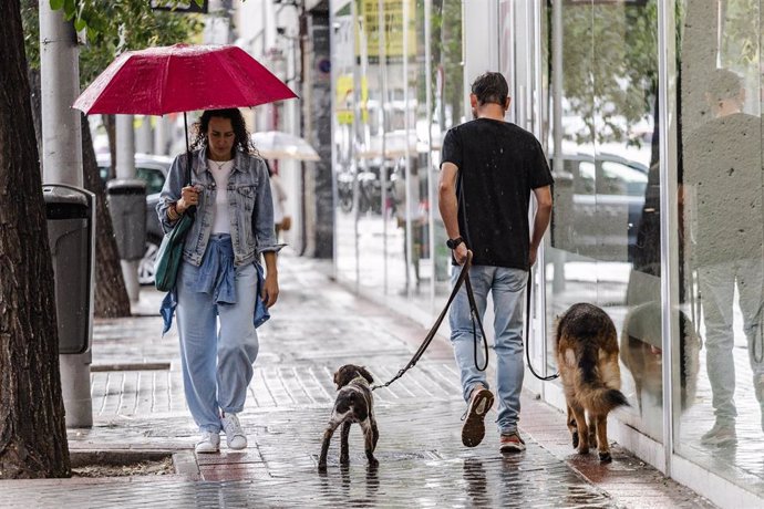 Archivo - Dos personas caminan bajo la lluvia, a 2 de septiembre de 2023, en Madrid (España). 