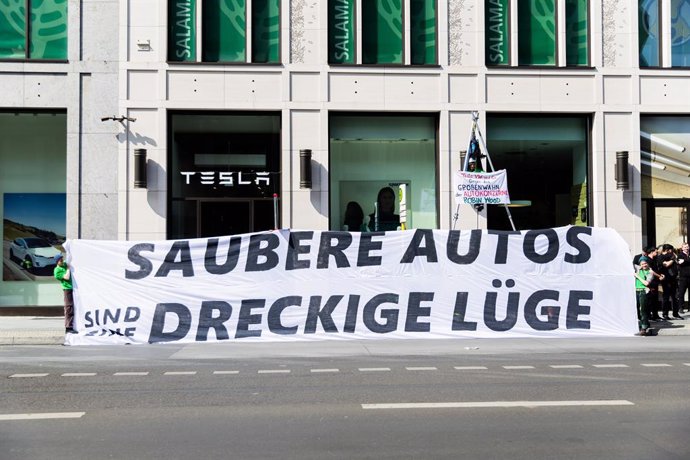 10 May 2024, Berlin: Protesters hold a banner in front of the Tesla store in the Mall of Berlin during a protest 