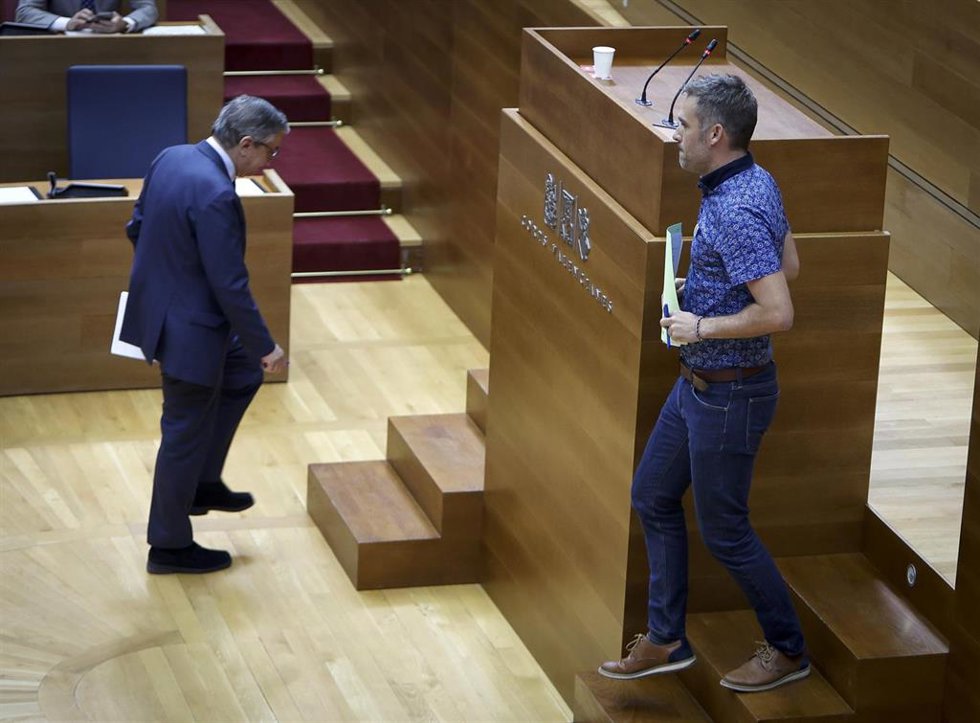 El conseller José Antonio Rovira (i) se cruza en el pleno de Les Corts con el diputado de Compromís Gerard Fullana