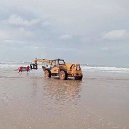 Un vehículo pesado saca del mar, en la playa de Oyambre, al turismo que quedó encallado
