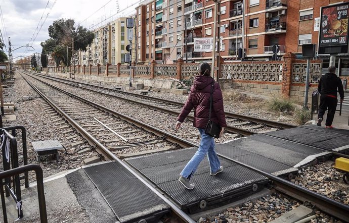 Archivo - Varias personas cruzan el paso a nivel de Alfafar