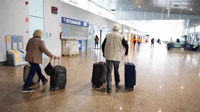 Archivo - Dos personas caminan con sus maletas en las instalaciones del aeropuerto de Vigo, a 21 de marzo de 2023, en Vigo, Pontevedra, Galicia (España). El aeropuerto de Peinador en Vigo ha cancelado hoy su actividad al descubrir un socavón en pista, lo 