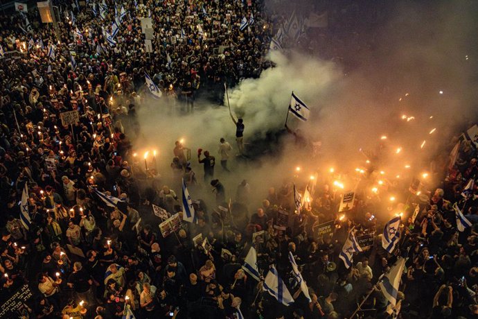 Archivo - March 30, 2024, Tel Aviv, Israel: Protestors with torches stand in the smoke after Israeli police extinguished a bonfire set by protestors during the demonstration. Tens of thousands of people demonstrated with the hostages families against Prim