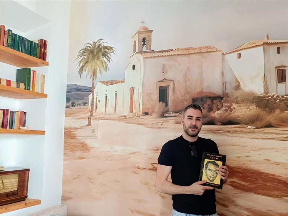 El ilustrador Antonio Lorente en el alojamiento dedicado a Federico García Lorca frente a la imagen del Cortijo del Fraile.