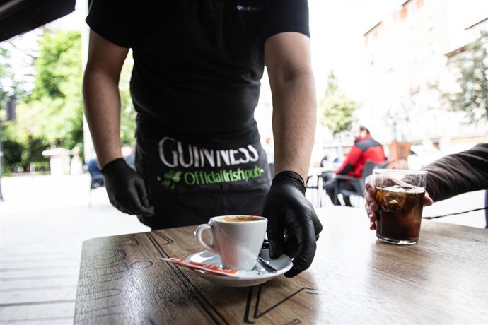 Archivo - Un camarero sirve un café en una terraza en el centro de Vitoria