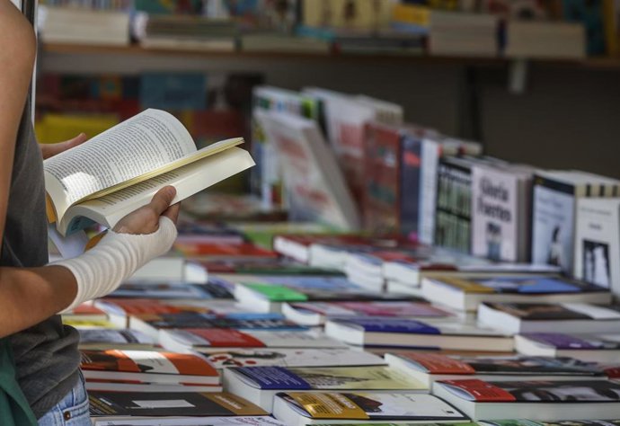 Archivo - Una persona sujeta un libro en una de las casetas de la Fira del Llibre de Valencia.