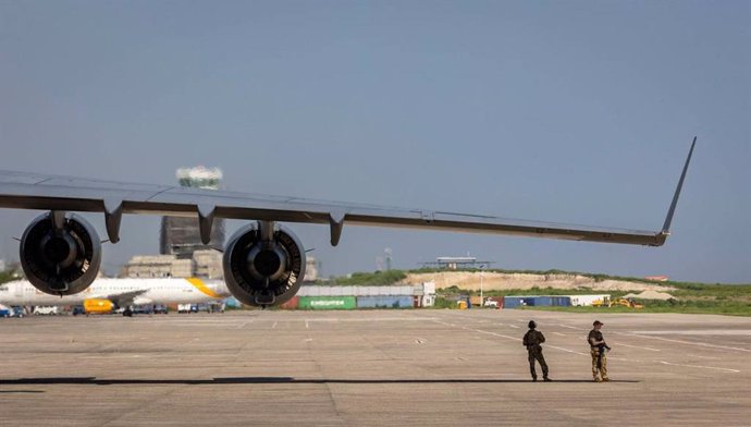 Dos militares de EEUU en la pista del Aeropuerto Internacional de Puerto Príncipe, en Haití, frente a un avión que transportaba suministros para el campamento que se está construyendo para la Policía de Kenia