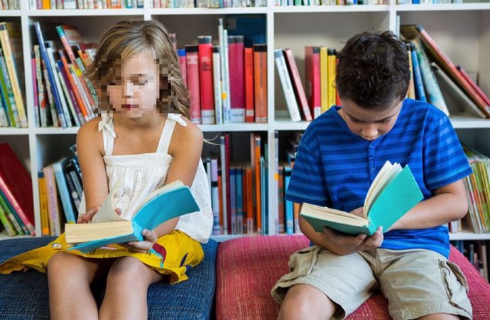 Dos niños leen un cuento en una biblioteca.