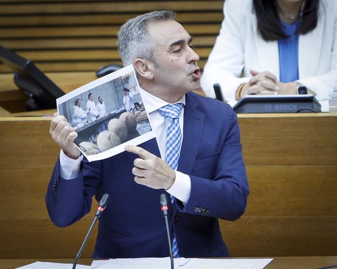El síndic del PP, Miguel Barrachina, muestra en el pleno de Les Corts una imagen del presidente del Gobierno, Pedro Sánchez, en un acto de exhumación