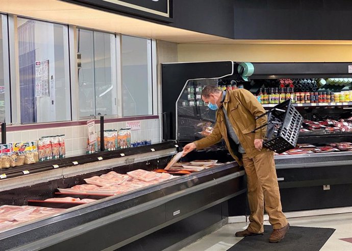 Archivo - Un hombre compra productos cárnicos en un supermercado.