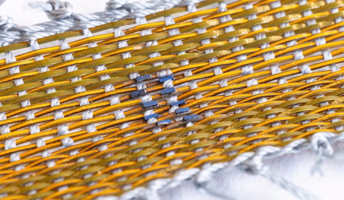 Los investigadores cortaron y ensamblaron pequeñas células solares en placas de circuitos delgadas y flexibles antes de sellarlas en un polímero protector para crear una hebra similar a una fibra que se tejió con nailon para formar un pequeño tejido.