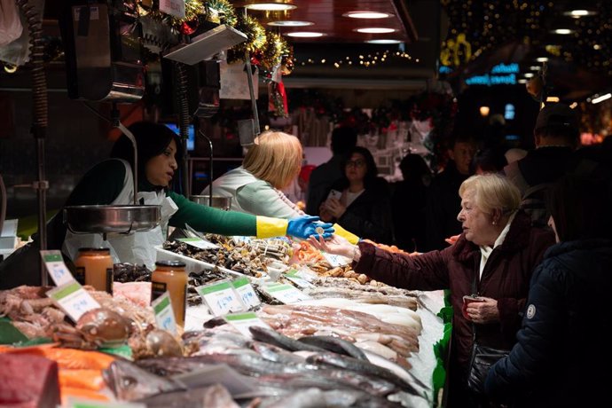 Archivo - Una comerciante cobra a una señora, en el Mercado de la Boquería, a 14 de diciembre de 2023, en Barcelona, Catalunya (España). El Mercado de San José, popularmente conocido como La Boquería