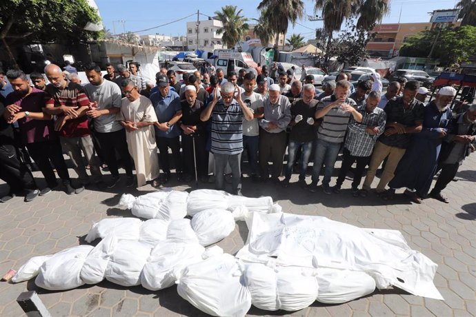 Un grupo de personas reza frente a más muertos por los bombardeos de Israel sobre Gaza.