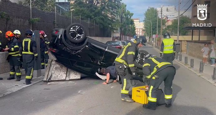Bomberos del Ayuntamiento de Madrid sacan al conductor atrapado en un vehículo volcado en el barrio madrileño de Chamartín.