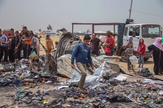 Palestios en los restos de un incendio provocado por un bombardeo israelí contra un campamento de desplazados en Rafá, en el sur de la Franja de Gaza