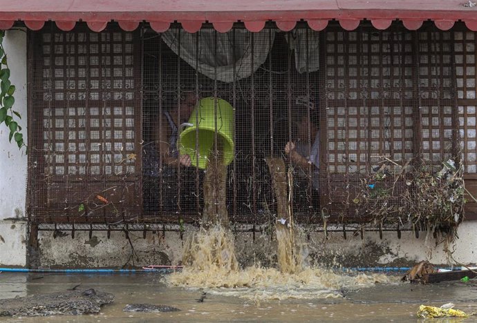 Archivo - Personas achicando agua de su vivienda en Filipinas a causa de una tormenta tropical.