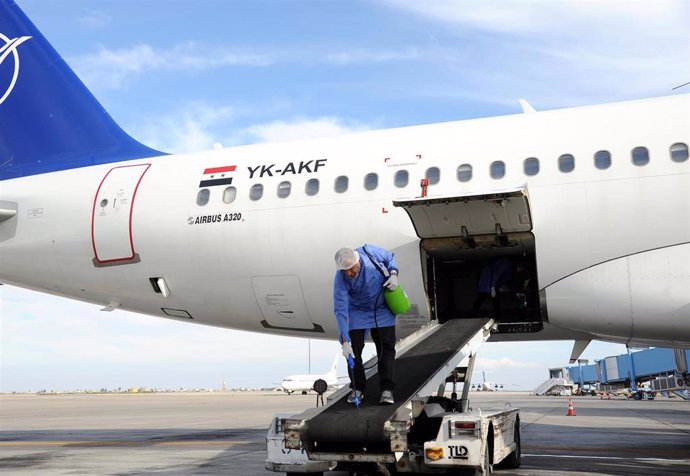 Archivo - Trabajos de desinfección de un avión en el aeropuerto de la capital de Siria, Damasco (archivo)