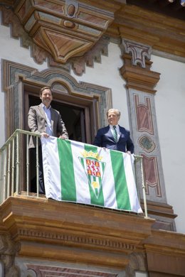 El presidente de la Diputación, Salvador Fuentes (dcha.), y el CEO del Córdoba CF, Antonio Fernández, colocan la bandera del club blanquiverde en el Palacio de la Merced.