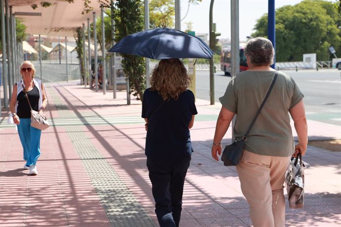 Archivo - Una mujer usa un paraguas para protegerse de las altas temperaturas.