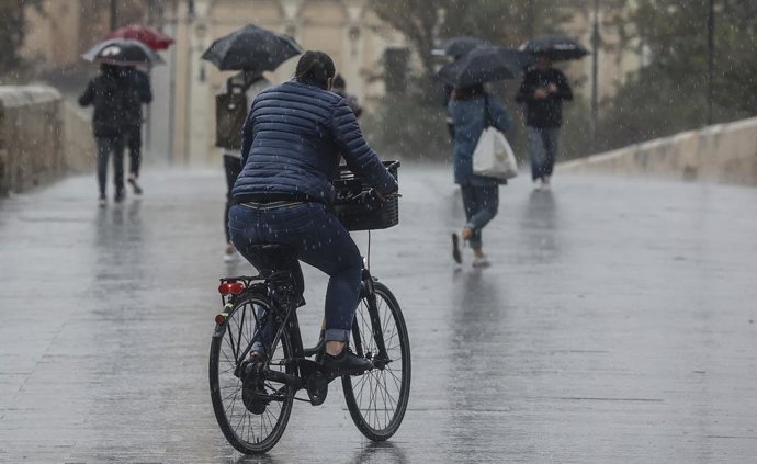 Archivo - Arxiu - Una persona circula amb bicicleta sota la pluja