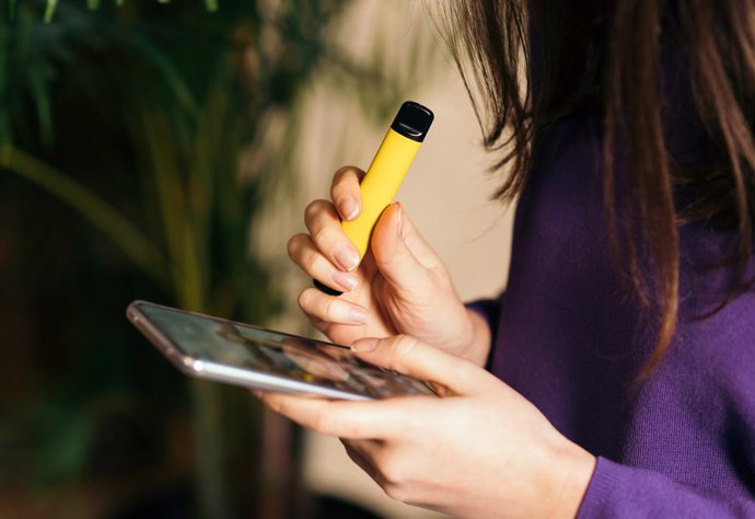 Archivo - Yellow disposable electronic cigarette in a woman's hand. Modern online communication.