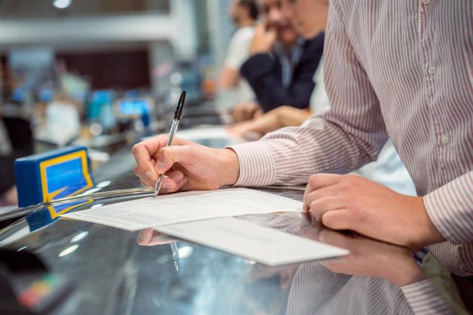 Archivo - Varias personas rellenan documentos tras solicitar el voto por correo en el Edificio de correos.