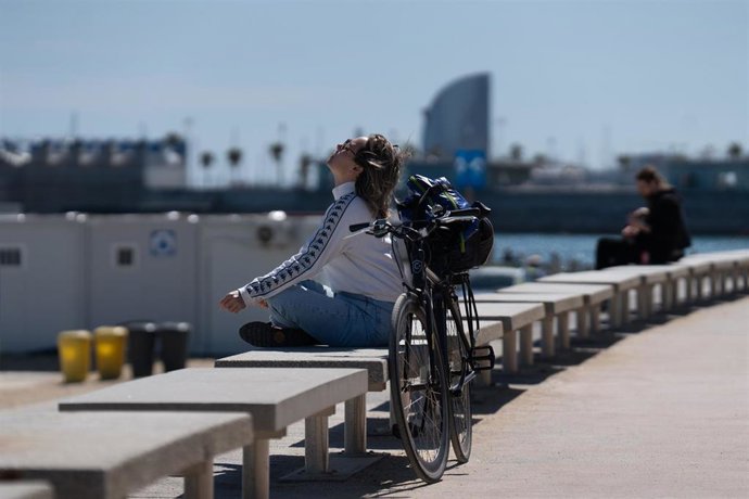 Archivo - Una mujer toma el sol en el paseo marítimo de la playa del Bogatell en Barcelona.