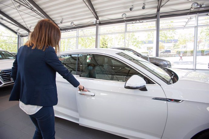 Archivo - Una mujer abre un coche aparcado en el interior de un concesionario