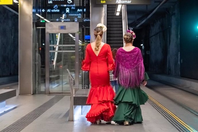 Dos mujeres vestidas de flamenca en una parada del metro de Granada.