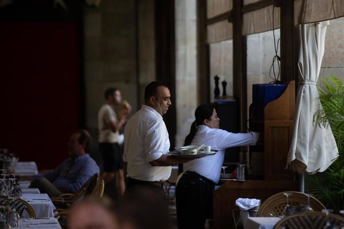 Archivo - Un camarero sostiene una bandeja en la plaza Real de Barcelona