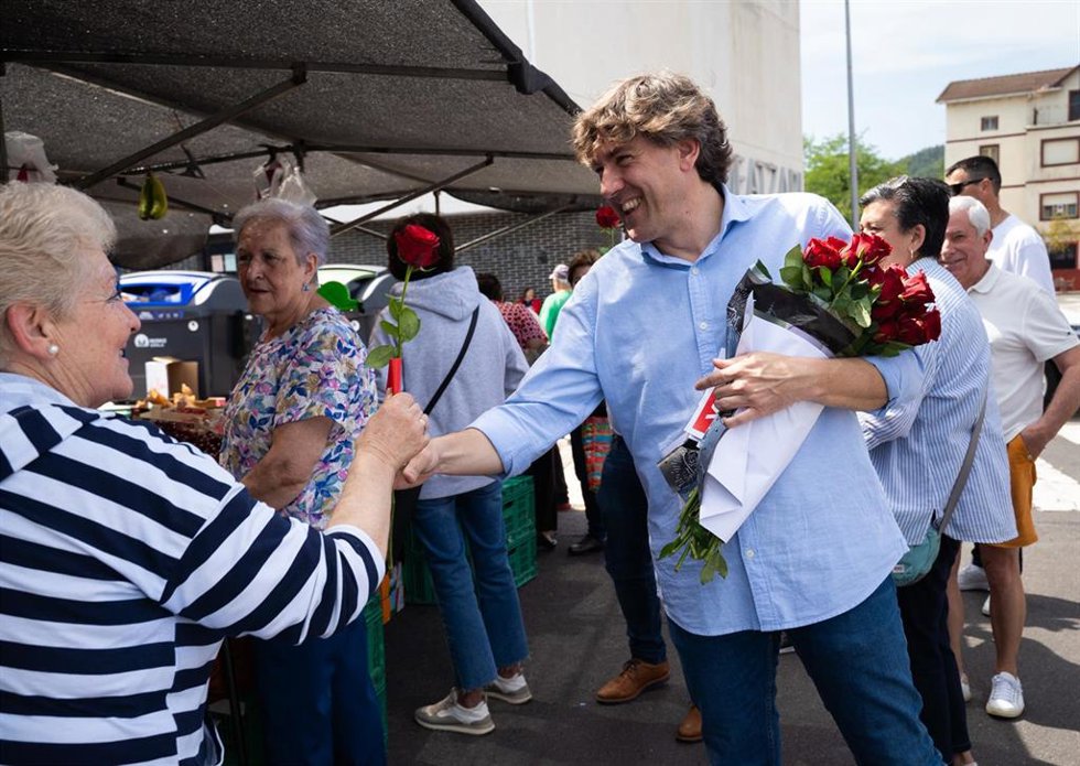 El secretario general del PSE-EE, Eneko Andueza, reparte rosas en el mercadillo de Muskiz, en Bizkaia.