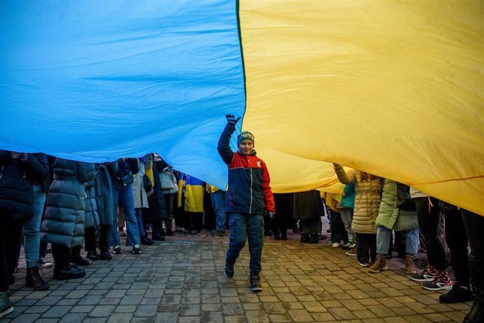 Archivo - February 24, 2024, Vilnius, Lithuania: A kid goes under a giant Ukrainian flag during a rally in support of Ukraine. A march and demonstration in support of Ukraine attended by about 1,000 people took place in Vilnius on the second anniversary o