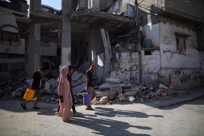 Un grupo de palestinos pasan ante un edificio destruido en Al Maghazi, en la Franja de Gaza