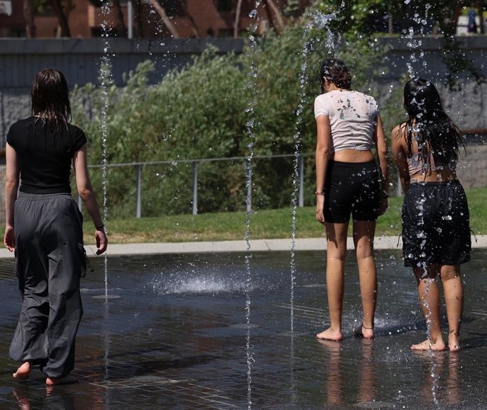 Jóvenes se mojan con chorros de agua en la playa de Madrid Río
