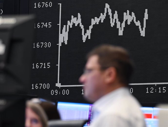 Archivo - 29 December 2023, Hesse, Frankfurt_Main: Stock exchange traders talk to each other in the trading hall of the Frankfurt Stock Exchange in front of the display board showing the Dax curve.